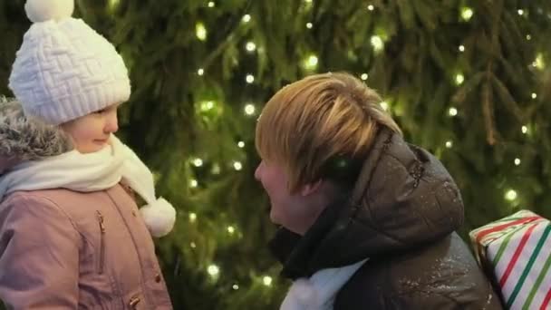 Mutlu Anne Dışarıda Noel Ağacının Arka Planında Kızına Bir Noel — Stok video