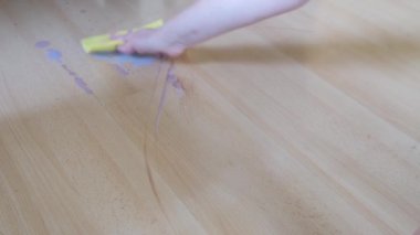 Adult hand wipe wet stain on parquet from spilled cocoa with rag take care of home house cleanliness
