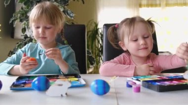 Happy sweet little girls, kids decorate eggs with paints. Preparation for Easter. Educational exercises for children. Preparation for Easter.