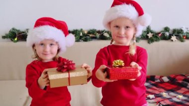 Noel Baba şapkalı güzel, gülümseyen küçük kız çocuğunun portresi. Elinde kurdeleli hediyeler var ve kameraya bakıyor. Mutlu yıllar tatil konsepti
