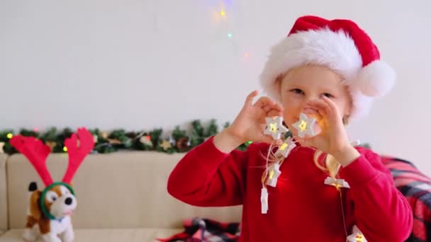 Улыбающаяся Девочка Шляпе Санта Клауса Смотрит Камеру Делает Смешное Лицо — стоковое видео
