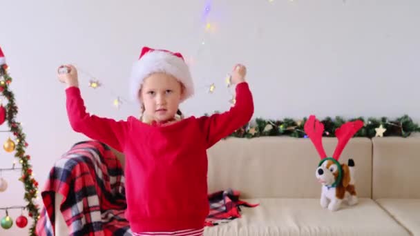 Glimlachend Meisje Kerstman Hoed Siert Zichzelf Met Kerstverlichting Voor Celebrated — Stockvideo