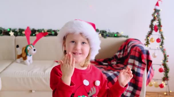 Uśmiechnięta Dziewczynka Kapeluszu Świętego Mikołaja Wysłać Pocałunek Powietrza Patrząc Kamerę — Wideo stockowe