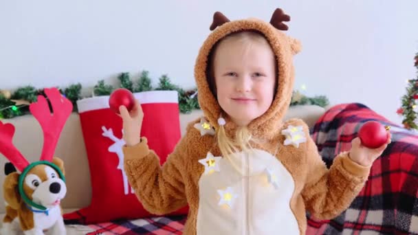 Geyik Kostümlü Gülümseyen Çocuk Kameraya Bakıp Yüzünde Kırmızı Noel Toplarıyla — Stok video