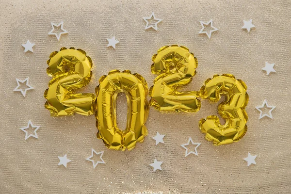 2023 gold foil balloons and confetti on gold glitter background. Festive concept.