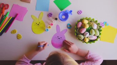 a little girl made an Easter egg out of paper and painted it with paints.DIY Easter home decor.Handmade. Project of childrens creativity, handicrafts, crafts for kids.