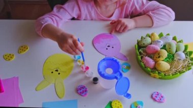 a little girl made an Easter egg out of paper and painted it with paints.DIY Easter home decor.Handmade. Project of childrens creativity, handicrafts, crafts for kids.