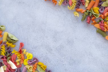 Frame of Variety of types and shapes of Italian pasta on concrete background. Italian cuisine food concept and menu design. Dry pasta background. Top view. Flat lay. Copy space.
