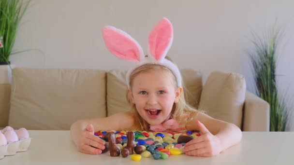Mała Blondynka Króliczych Uszach Wygląda Szczęśliwą Przytula Dużo Czekoladowych Jajek — Wideo stockowe