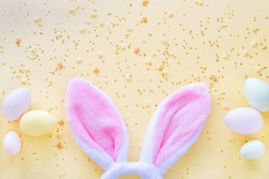 Easter eggs and bright bunny ears on yellow background. Flat lay top view. Concept holiday easter.