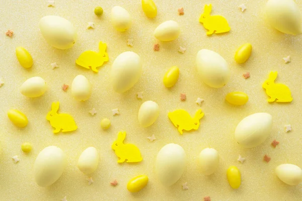 Yellow eggs with rabbit and sweet confetti pattern on yellow background. Egg hunting.