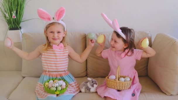 Дві Маленькі Сестрички Кролячих Вухах Сидять Дивані Граючи Великодніми Яйцями — стокове відео