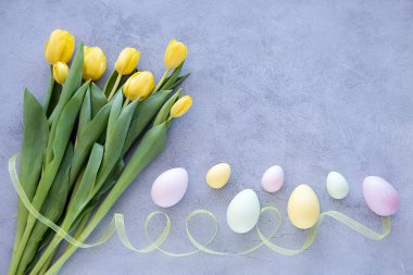 Beton arka planda renkli paskalya yumurtaları olan sarı lale buketi. Fotokopi alanı olan bahar ve Paskalya bayramı kavramı..