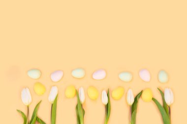 Açık arkaplanda renkli paskalya yumurtaları olan güzel beyaz laleler. Fotokopi alanı olan bahar ve Paskalya bayramı kavramı..
