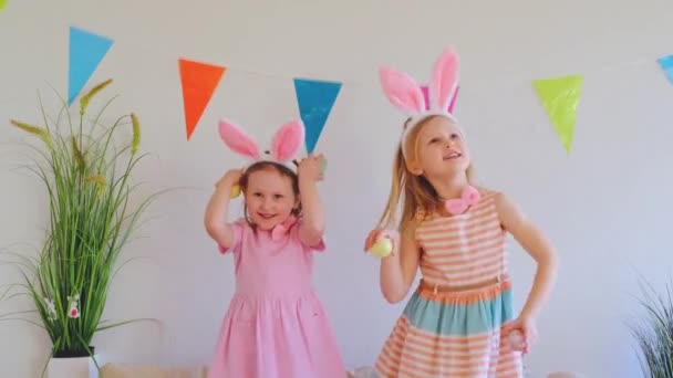 Дві Щасливі Маленькі Сестрички Кролячих Вухах Стрибають Танцюють Дивані Тримаючи — стокове відео