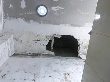 Kırık tavan panelleri eski kirli odada büyük bir delikle hasar görmüş.