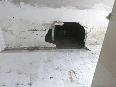Kırık tavan panelleri eski kirli odada büyük bir delikle hasar görmüş.