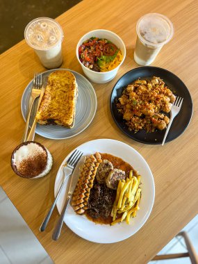 Masa, kahve, tost, pirinç kasesi gibi çeşitli lezzetli yiyeceklerin üst görüntüsü.