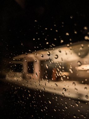 Camdaki su damlacıkları, ıslak arabanın camındaki gece lambası..