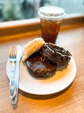 Beyaz tabakta farklı malzemelerle servis edilen lezzetli çörekler ve bir fincan kahve.