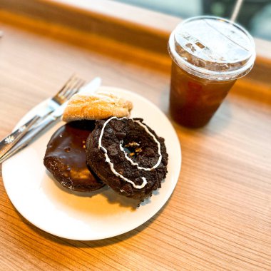 Beyaz tabakta farklı malzemelerle servis edilen lezzetli çörekler ve bir fincan kahve.