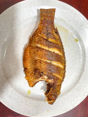 Kızarmış Tilapia ya da Nila Goreng beyaz tabakta servis yaparlar.