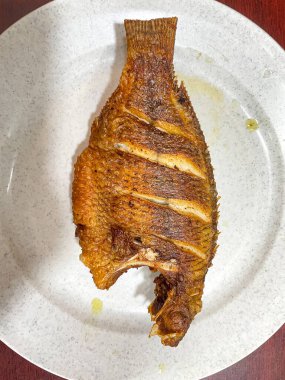 Kızarmış Tilapia ya da Nila Goreng beyaz tabakta servis yaparlar.