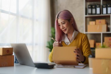 Serbest Asyalı Kadın Girişimcisi olarak açılışta kutulu bir dizüstü bilgisayar kullanarak online pazarlama paketleme kutusu ve KOBİ fikir konseptini dağıtma başarısı.