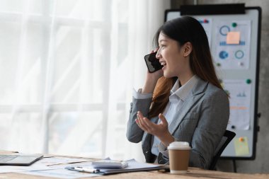Ofiste cep telefonuyla çalışan Asyalı güzel bir iş kadını. iş finans kavramı.
