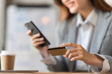 Kredi kartı ve cep telefonu kullanan genç biri. Çevrimiçi alışveriş, e-ticaret kavramı.