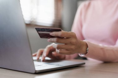 Young person using credit card and laptop computer. Online shopping, e-commerce concept.