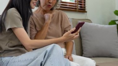 Üst düzey kadın ve yetişkin kız aileleriyle iletişim kuran cep telefonu ekranlarına bakıyorlar. Yaşlı kadın video araması için cep telefonu kullanıyor..