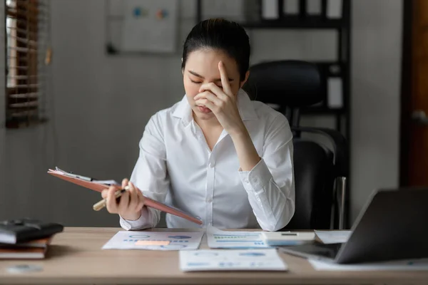Stressed Asian business woman worry with many document on desk at office. Businesswoman working at home.