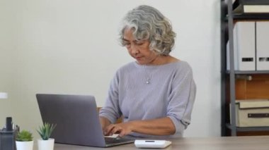 Hesap makinesi kullanan yaşlı bir iş kadını, banka hesaplarını yöneten yaşlı bir kadın, bütçe vergisini hesaplayan, banka borçlarını ödemeyi planlayan bir kadın..