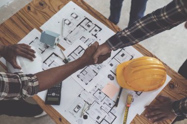 Mimar ve mühendis inşaat işçileri ofis inşaatındaki bir anlaşmayı bitirdikten sonra el sıkışıyorlar, başarı işbirliği konsepti.