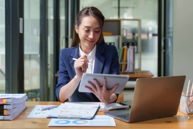 İş yerinde dizüstü bilgisayar kullanan bir kadın. İş kadını dijital tabletle ekonomi raporu hazırlıyor.