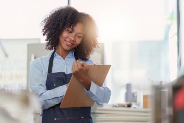 Restoranda dizüstü bilgisayarlı genç bir bayan yönetici. Açık tabelası olan kadın kahve dükkanı sahibi. Küçük işletme kavramı.
