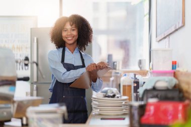 Restoranda dizüstü bilgisayarlı genç bir bayan yönetici. Açık tabelası olan kadın kahve dükkanı sahibi. Küçük işletme kavramı.