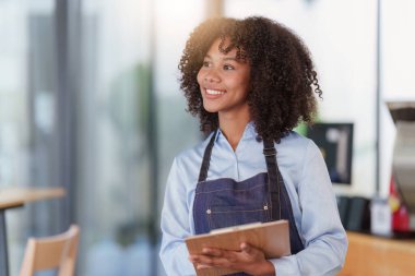 Restoranda dizüstü bilgisayarlı genç bir bayan yönetici. Açık tabelası olan kadın kahve dükkanı sahibi. Küçük işletme kavramı.