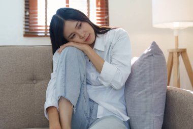 Genç Asyalı kadın kendini evdeki kanepede yalnız ve mutsuz hissediyor..