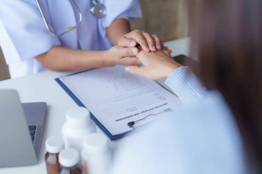 Semptomu açıklarken hastayla sohbet eden ve cesaretlendirmek için el ele tutuşan doktor..