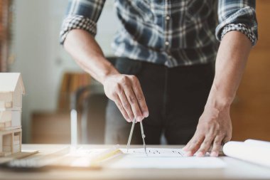 Ofisteki planlarla uğraşırken mimari bir şeyler çiziyor. Mimarlık ve Mühendislik kavramı.