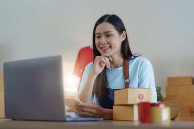 Asyalı Kadın moda tasarımcısı yeni koleksiyon için çalışan yaratıcı terzi. Mutlu çevrimiçi mağaza sahibi nakliye siparişi hazırlıyor.