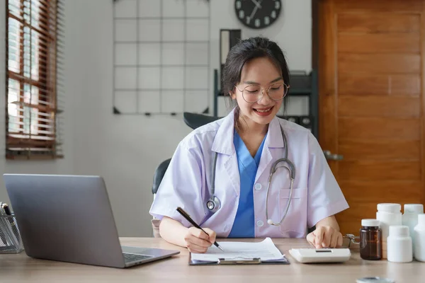 Portrait of female Asian doctor working with patient document in her office at clinic.