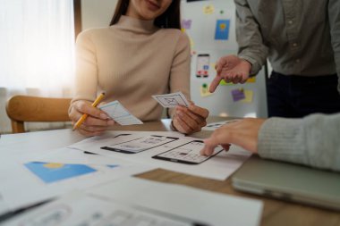 Genç Asyalı yaratıcı ofiste yeni bir iş kuruyor. Modern bir şirket kurma takımı. Meslektaşları ui, ux küçük işletme.