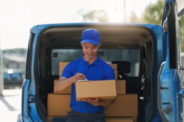 Paket ve teslimat konsepti olan Asyalı kurye. Dijital tablet kullanan teslimatçı..