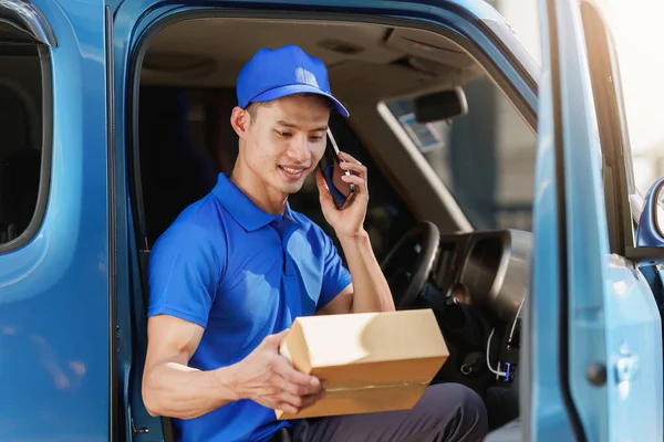 Asian courier with parcel and delivery logistic concept. Delivery man talking with customer by phone.