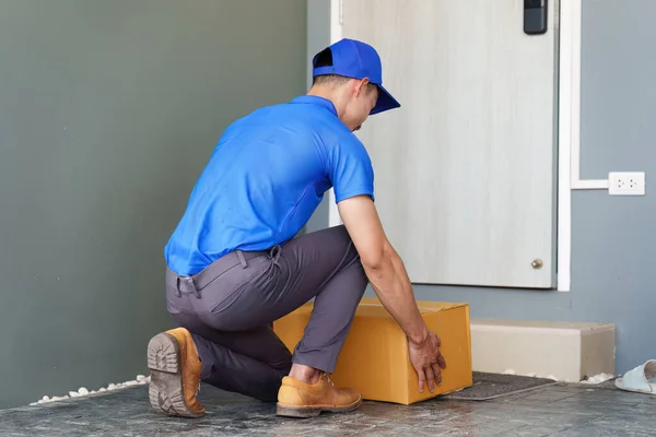 Asian courier with parcel and delivery logistic concept. Delivery man dropping the parcel in front of customer door house.