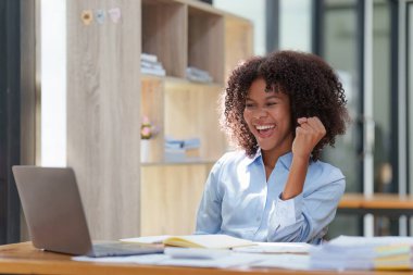Dizüstü bilgisayarda çalışan siyahi iş kadını mutlu bir şekilde kazanıyor. Heyecanlı kadın zaferi işten iyi haberler alıyor..