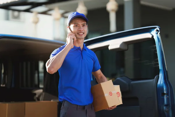 Asian courier with parcel and delivery logistic concept. Delivery man talking with customer by phone.